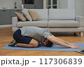 Training to become the best. Beautiful young man in sports clothing exercising at home. 117306839