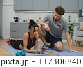 Training to become the best. Beautiful young woman and man in sports clothing exercising at home. 117306840