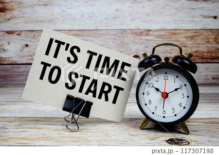 It's time to start text on paper card with alarm clock on wooden background 117307198