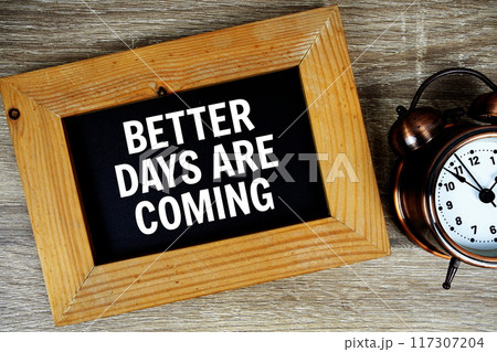 Better days are coming text on wooden board with alarm clock on wooden background 117307204