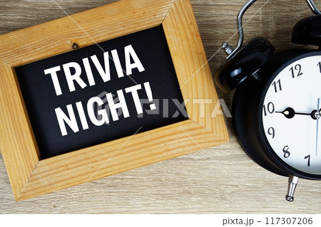 Trivia Night text on chalkboard with alarm clock top view on wooden background 117307206