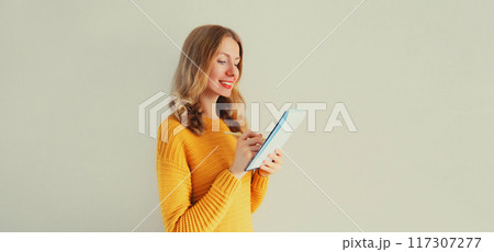 Portrait of young caucasian woman writing down memories in notebook diary on gray background 117307277