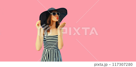 Summer portrait beautiful young woman model blowing kiss in black round straw hat on pink background Summer portrait beautiful young woman model blowing kiss in black round straw hat on pink background 117307280