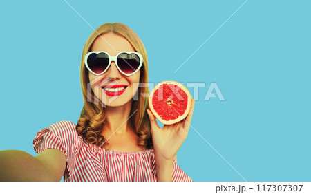 Summer portrait of happy smiling woman taking selfie with phone, fruit in heart shaped glasses Summer portrait of happy smiling woman taking selfie with phone, fruit in heart shaped glasses 117307307