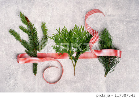 Red and white ribbon with three Christmas tree branches flat lay. Merry Christmas and Happy New Year seasons greetings card. Banner with copy space 117307343