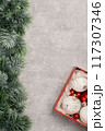 Red and white Christmas baubles in a box flat lay. Merry Christmas and Happy New Year seasons greetings card. Copy space. Festive border with fur tree branch 117307346