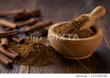 cinnamon powder in a wooden bowl  on a dark  wooden table, selective focus. 117308396