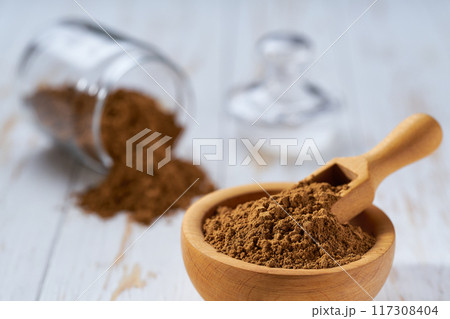 cinnamon powder in a wooden bowl on a white wooden table, selective focus. cinnamon powder in a wooden bowl on a white wooden table, selective focus. 117308404