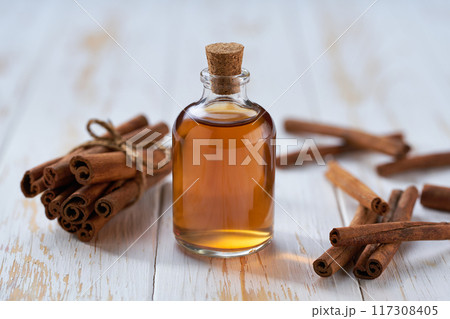 Cinnamon sticks and bottle of cinnamon oil on a white wooden table. 117308405
