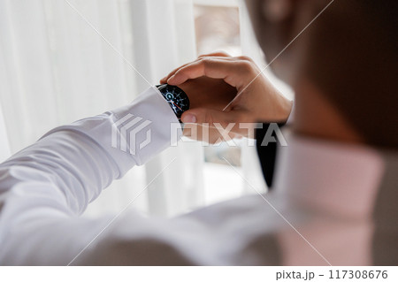 Businessman adjusting his watch, symbolizing precision and professionalism in a corporate setting 117308676