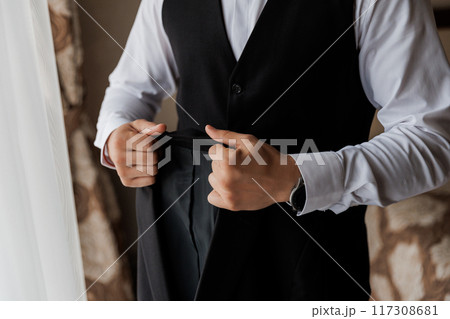Businessman adjusting his suit jacket, emphasizing professionalism and attention to detail in office 117308681