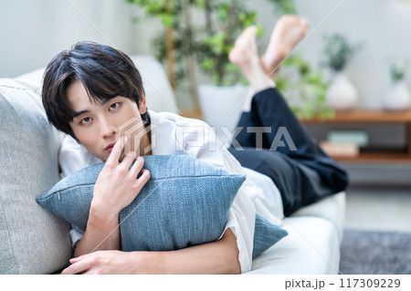 ソファーに寝転ぶ若い男性 117309229