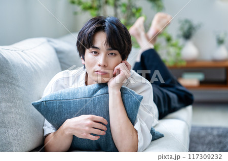 ソファーに寝転ぶ若い男性 117309232