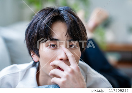 ソファーに寝転ぶ若い男性 117309235