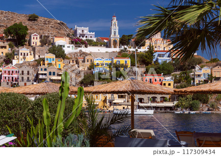 Colourful house facades and fishing boats in the bay of Symi village at sunset. 117309434