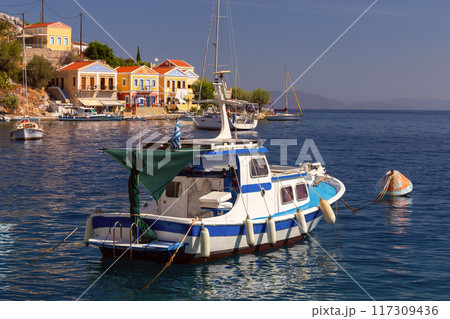 Colourful house facades and fishing boats in the bay of Symi village at sunset. Colourful house facades and fishing boats in the bay of Symi village at sunset. 117309436