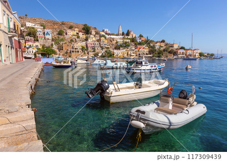 Colourful house facades and fishing boats in the bay of Symi village at sunset. Colourful house facades and fishing boats in the bay of Symi village at sunset. 117309439