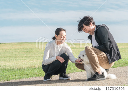 公園で犬の散歩をする愛犬家の夫婦・家族・ファミリー（中年・ミドル） 117310803