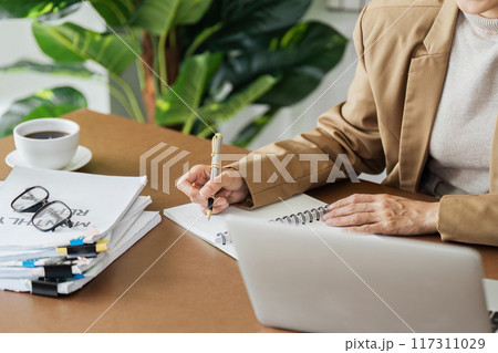 Business woman working in office writing plan on note book and use computer laptop to plan marketing strategy 117311029