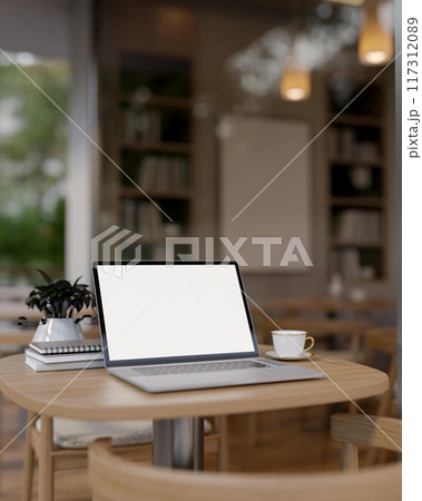 A laptop computer with a white-screen mockup on a wooden table in a cozy contemporary coffee shop. 117312089