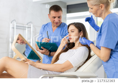Elderly woman cosmetologists explaining facial procedure to female patient 117312163
