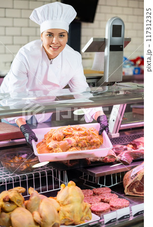Young woman puts chicken meat in showcase Young woman puts chicken meat in showcase 117312325