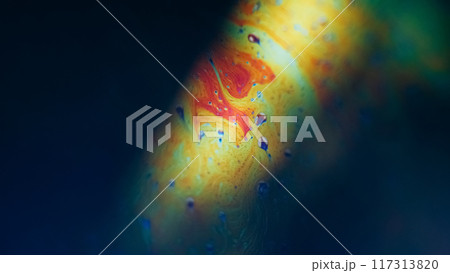 Ink rainbow. Psychedelic fluid. Defocused yellow blue green color oil chemical gasoline liquid droplets flow on dark black abstract art background. 117313820