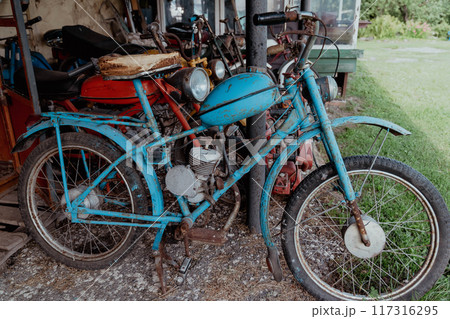 A vintage motorized bicycle is parked in a rustic shed A vintage motorized bicycle is parked in a rustic shed 117316295