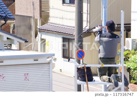 外灯に防犯カメラを取り付ける男性 117316747