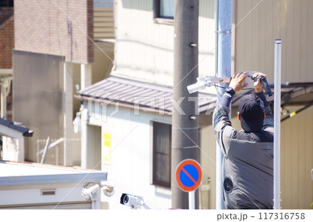 外灯に防犯カメラを取り付ける男性 117316758