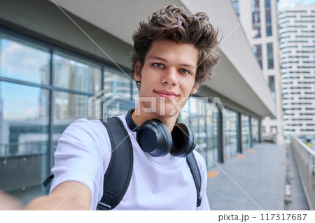 Selfie portrait of young handsome man with curly hair, outdoor 117317687
