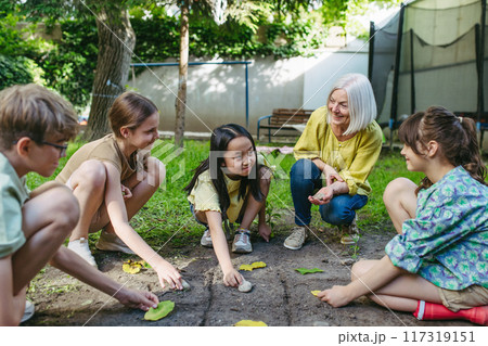 Students playing tic-tac-toe with stones and leaves, grid in soil. Outdoor sustainable education class. Students playing tic-tac-toe with stones and leaves, grid in soil. Outdoor sustainable education class. 117319151