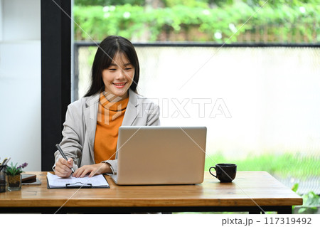 Asian businesswoman using laptop and analyzing financial data sheets on the table 117319492