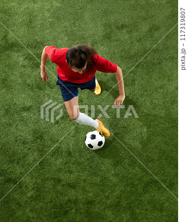 Aerial view of female football athlete training dribbling technique on green lush stadium. Workout for win. Aerial view of female football athlete training dribbling technique on green lush stadium. Workout for win. 117319807