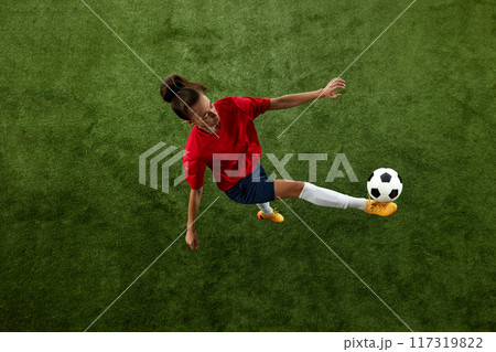 Aerial view of young fit woman training kicking ball and balancing on green lash stadium. Healthy lifestyle. Aerial view of young fit woman training kicking ball and balancing on green lash stadium. Healthy lifestyle. 117319822