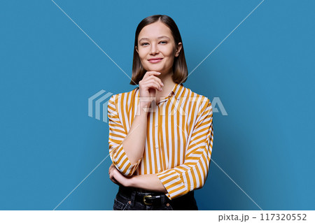 Young beautiful smiling woman on blue background Young beautiful smiling woman on blue background 117320552