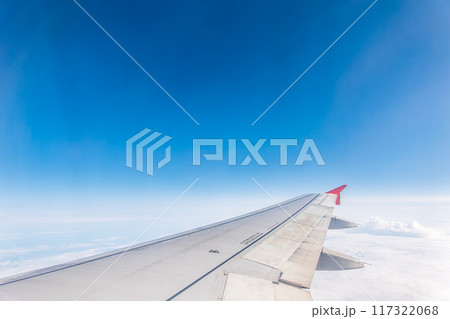 View from the airplane window at a beautiful cloudy sky and the airplane wing View from the airplane window at a beautiful cloudy sky and the airplane wing 117322068