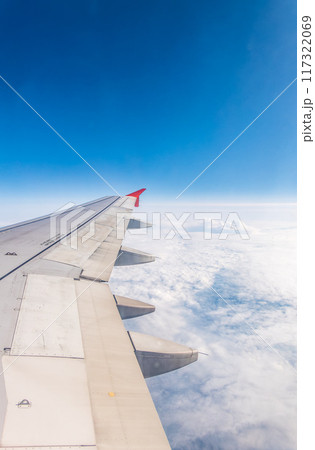View from the airplane window at a beautiful cloudy sky and the airplane wing 117322069