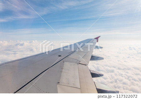 View from the airplane window at a beautiful cloudy sky and the airplane wing 117322072