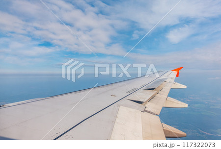 View from the airplane window at a beautiful cloudy sky and the airplane wing View from the airplane window at a beautiful cloudy sky and the airplane wing 117322073