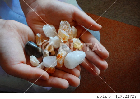 子供の手のひらに乗せた沢山の小さな天然石 117322728