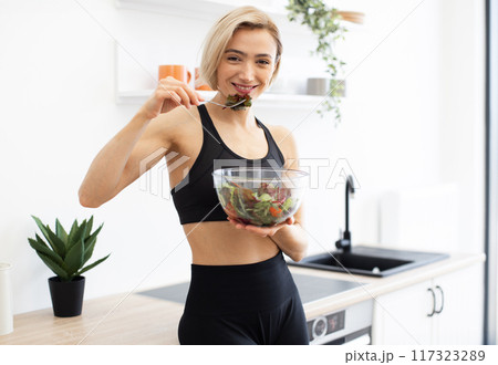 Woman enjoying healthy salad in modern kitchen Woman enjoying healthy salad in modern kitchen 117323289