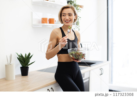 Woman enjoying healthy salad in modern kitchen 117323308
