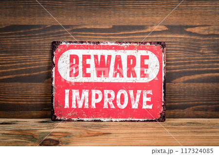 Improve. Beware sign with text on a wooden texture office table 117324085