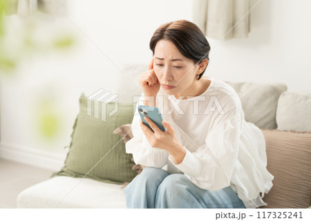 スマホを見て悩む女性 117325241