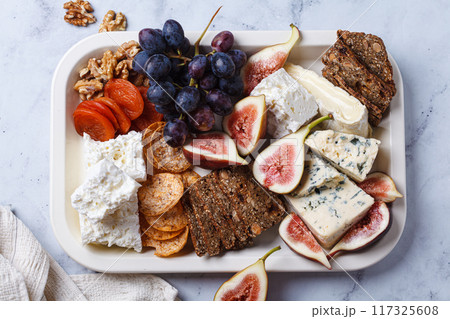 Variety of cheeses and fruits plate with wine, on white marble table. Variety of cheeses and fruits plate with wine, on white marble table. 117325608