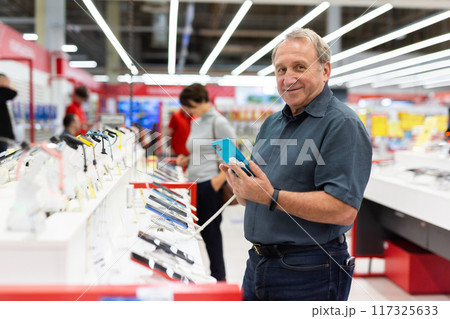 Elderly man chooses mobile phone in store Elderly man chooses mobile phone in store 117325633