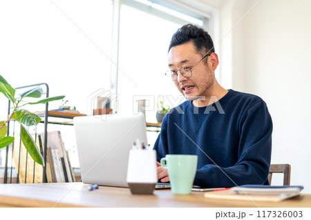 パソコンで作業している最中に画面を見て気まずそうな、若干驚いたような表情を浮かべる男性 117326003
