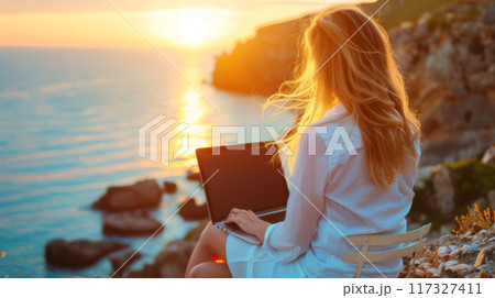 Woman Working on Laptop During Sunset on Rocky Cliff 117327411