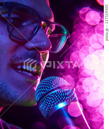 Close-up photo of singer's face, bathed in colorful stage lights, captures electric energy and emotion of moment. Close-up photo of singer's face, bathed in colorful stage lights, captures electric energy and emotion of moment. 117329305